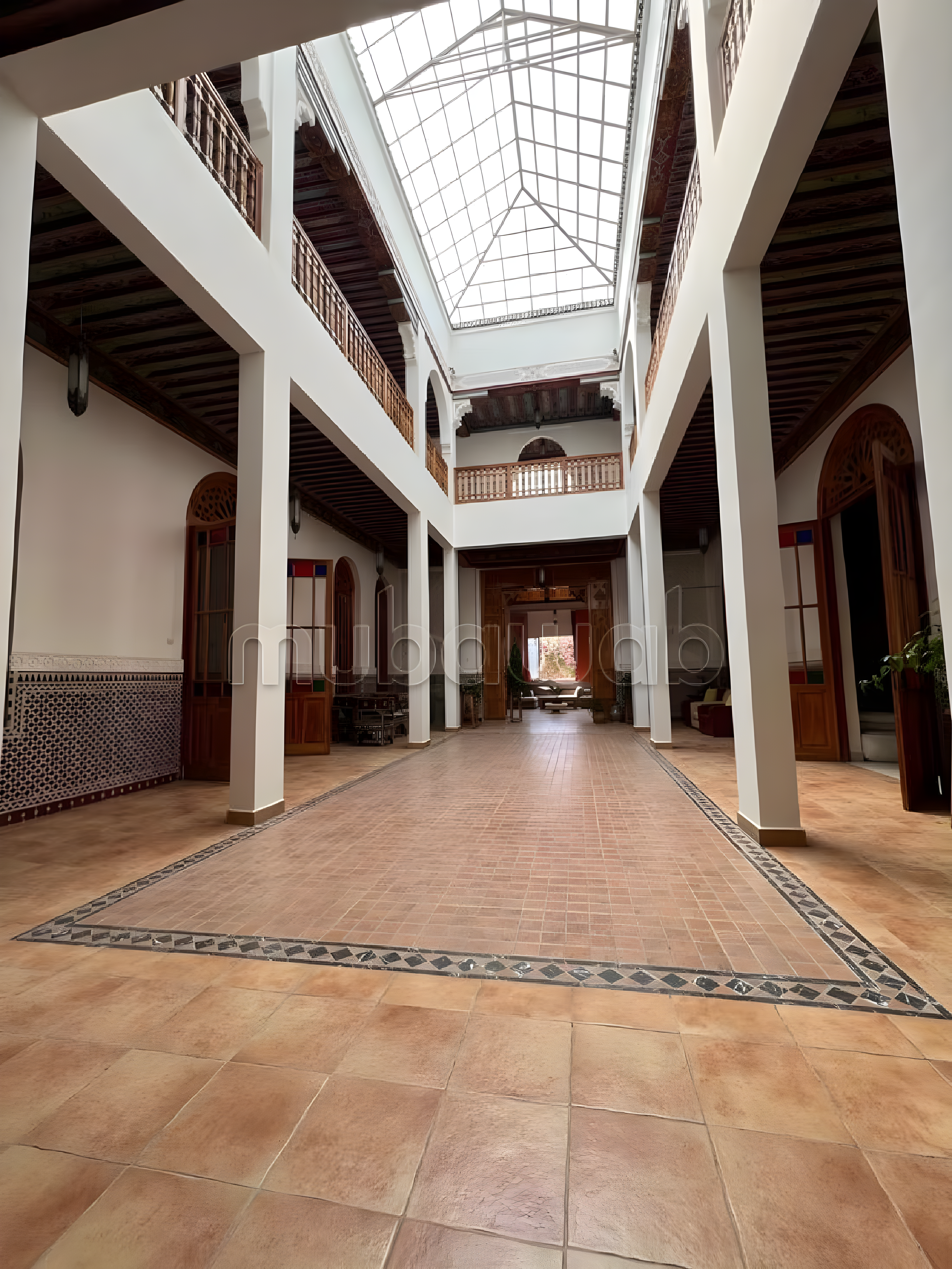 Courtyard in Ennakhil guesthouse with skylight roof and tiled flooring.