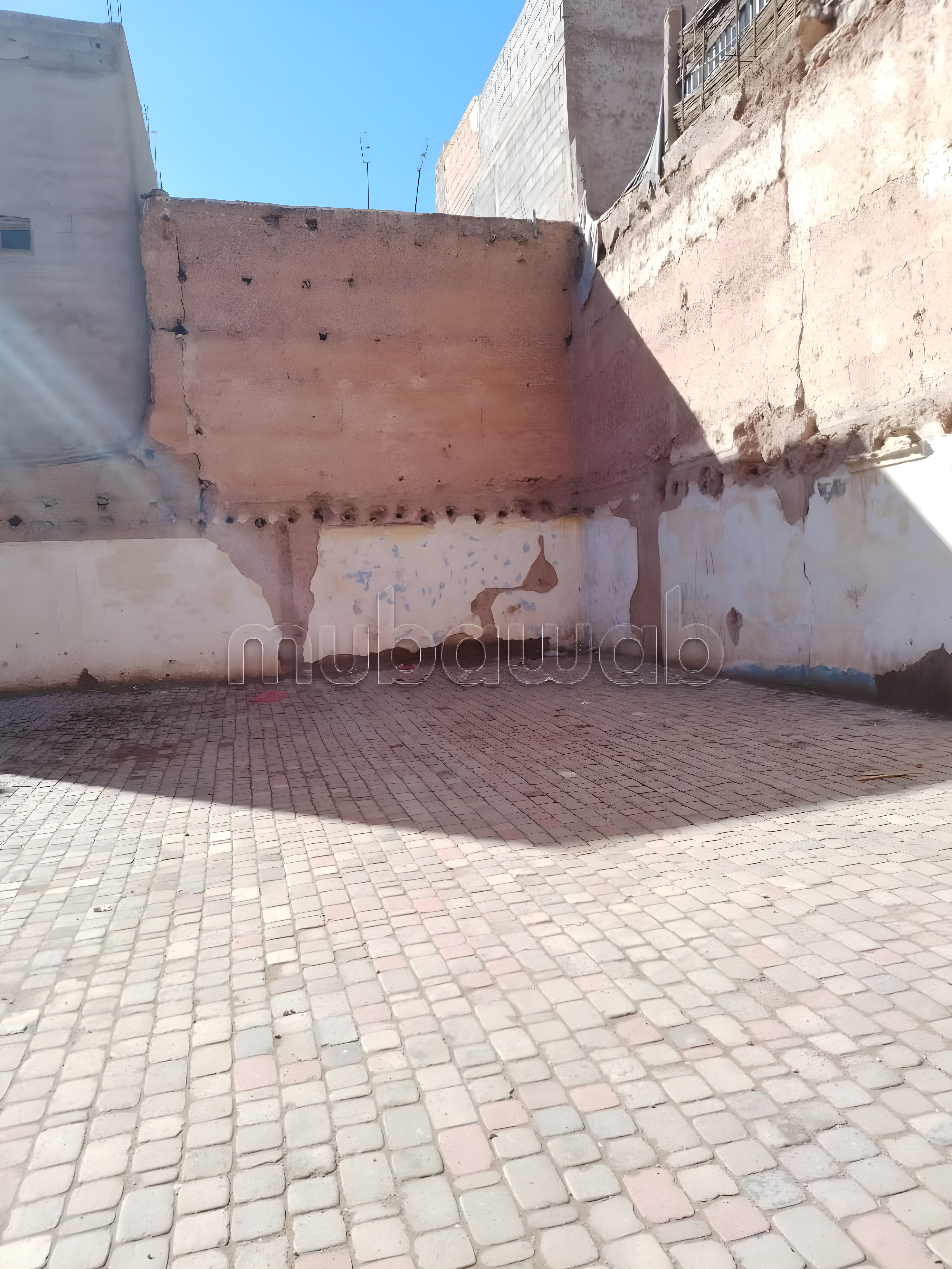 Open courtyard in Arset Ihiri guesthouse with brick flooring and weathered walls.
