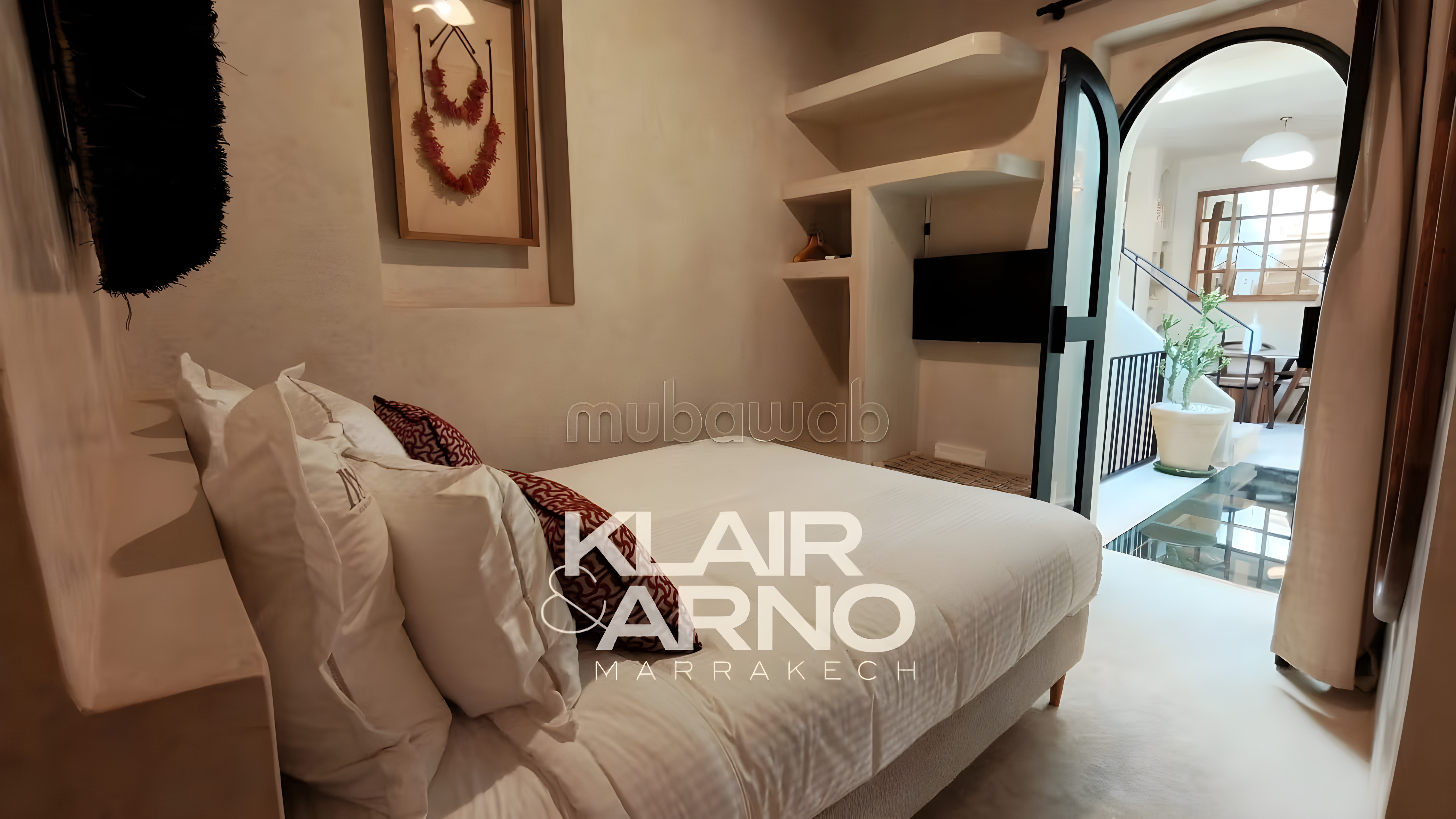 Traditional bedroom in Kennaria guesthouse with white linens, art, shelving, archway, and staircase.