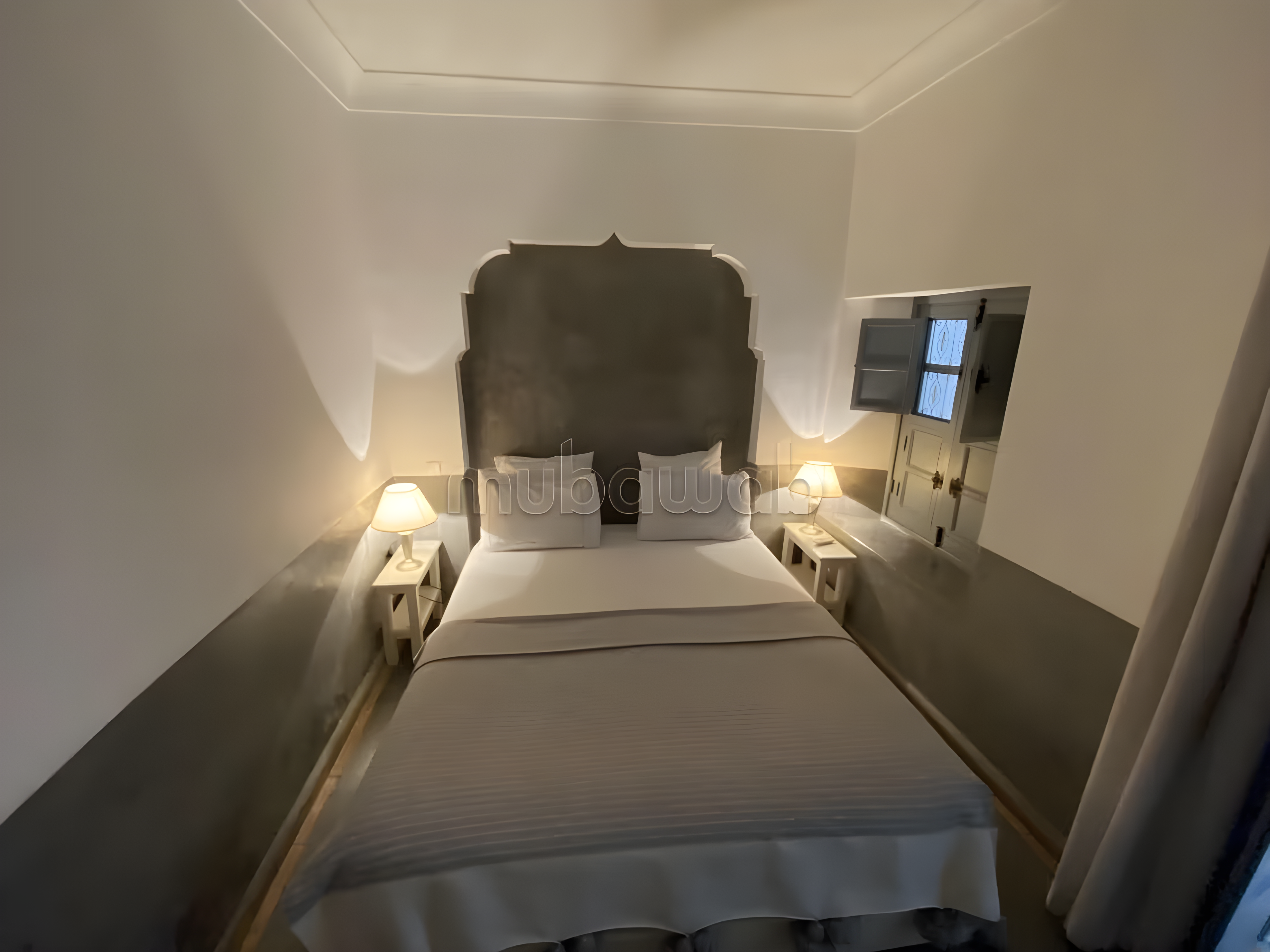 Moroccan-style bedroom in Riad Zitoun guesthouse with decorative headboard and wooden shutters.