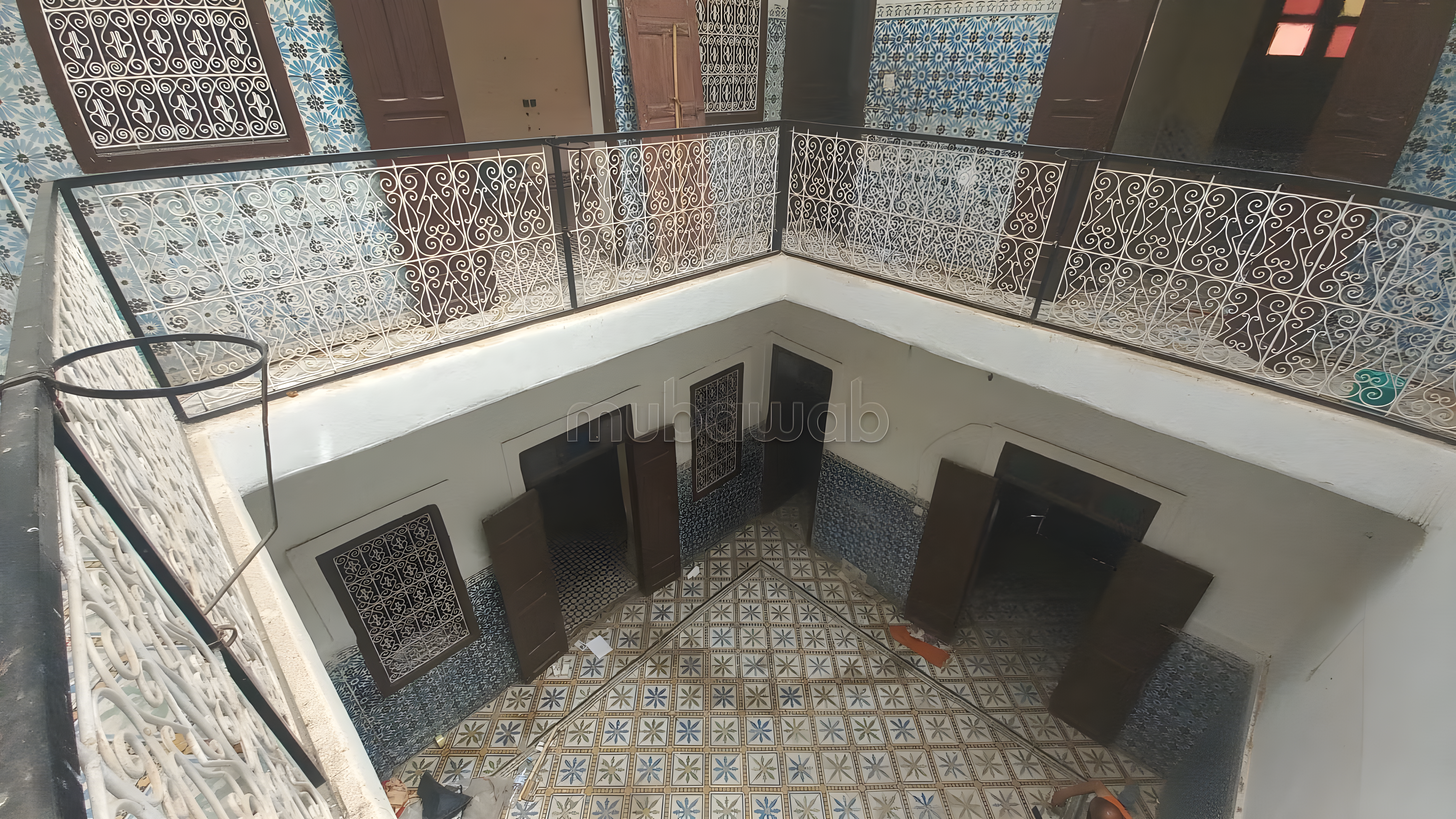 Tiled courtyard with wrought iron railings and wooden doorways in Sidi Mansour.