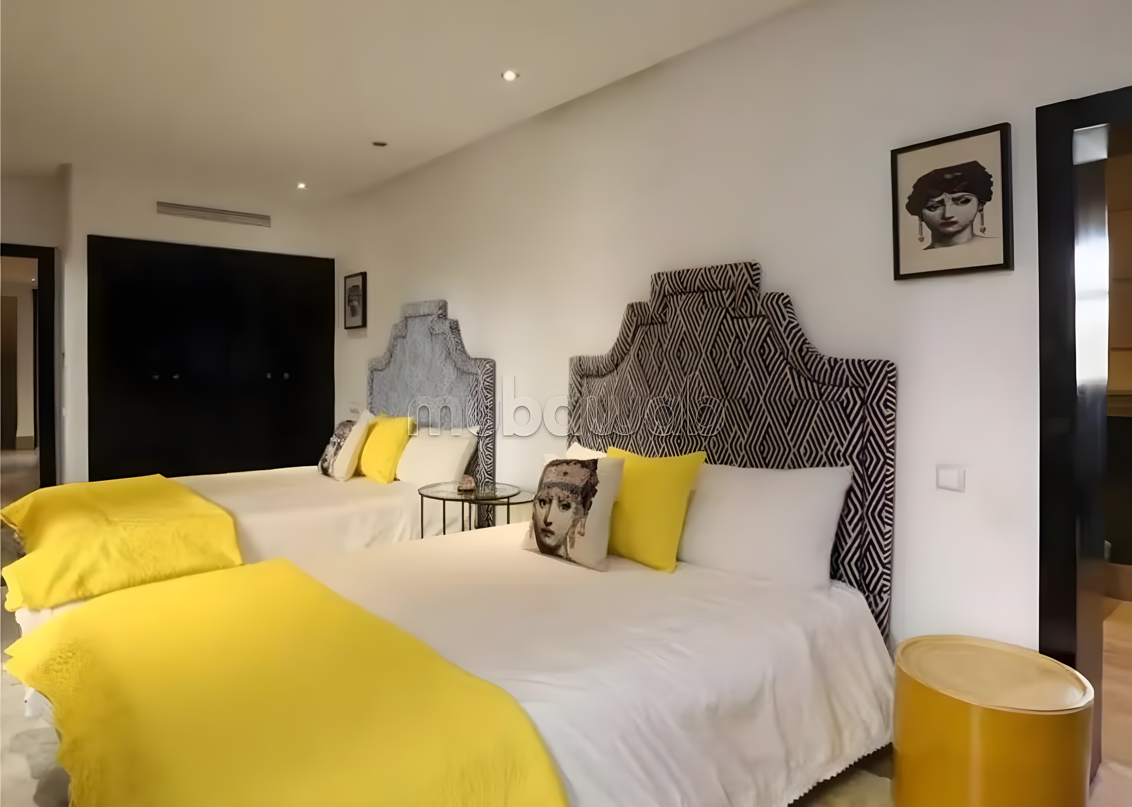 Guesthouse bedroom in Agdal with twin beds, patterned headboards, and yellow accents.