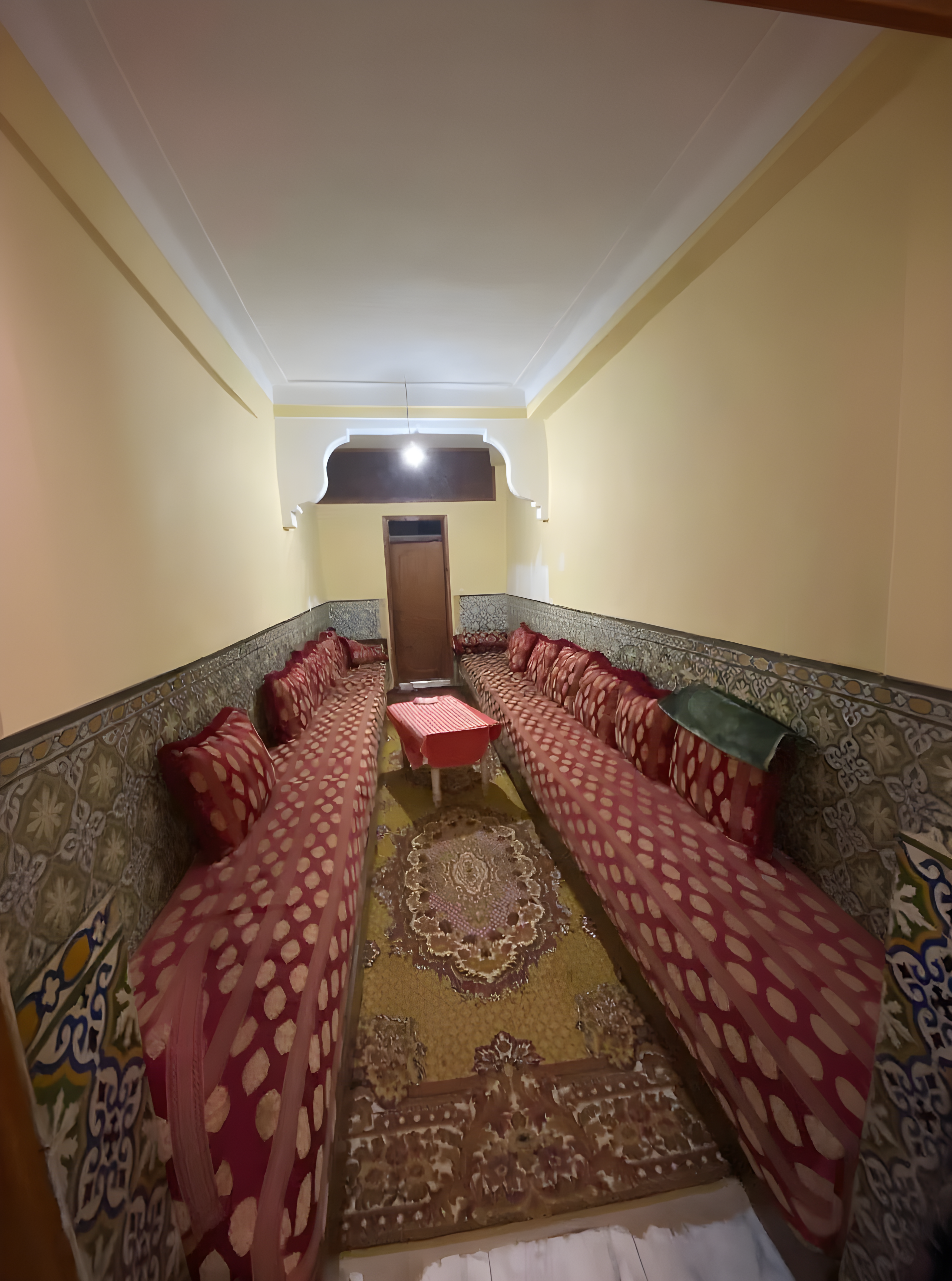 Traditional Moroccan salon with red curtains and tiled walls.
