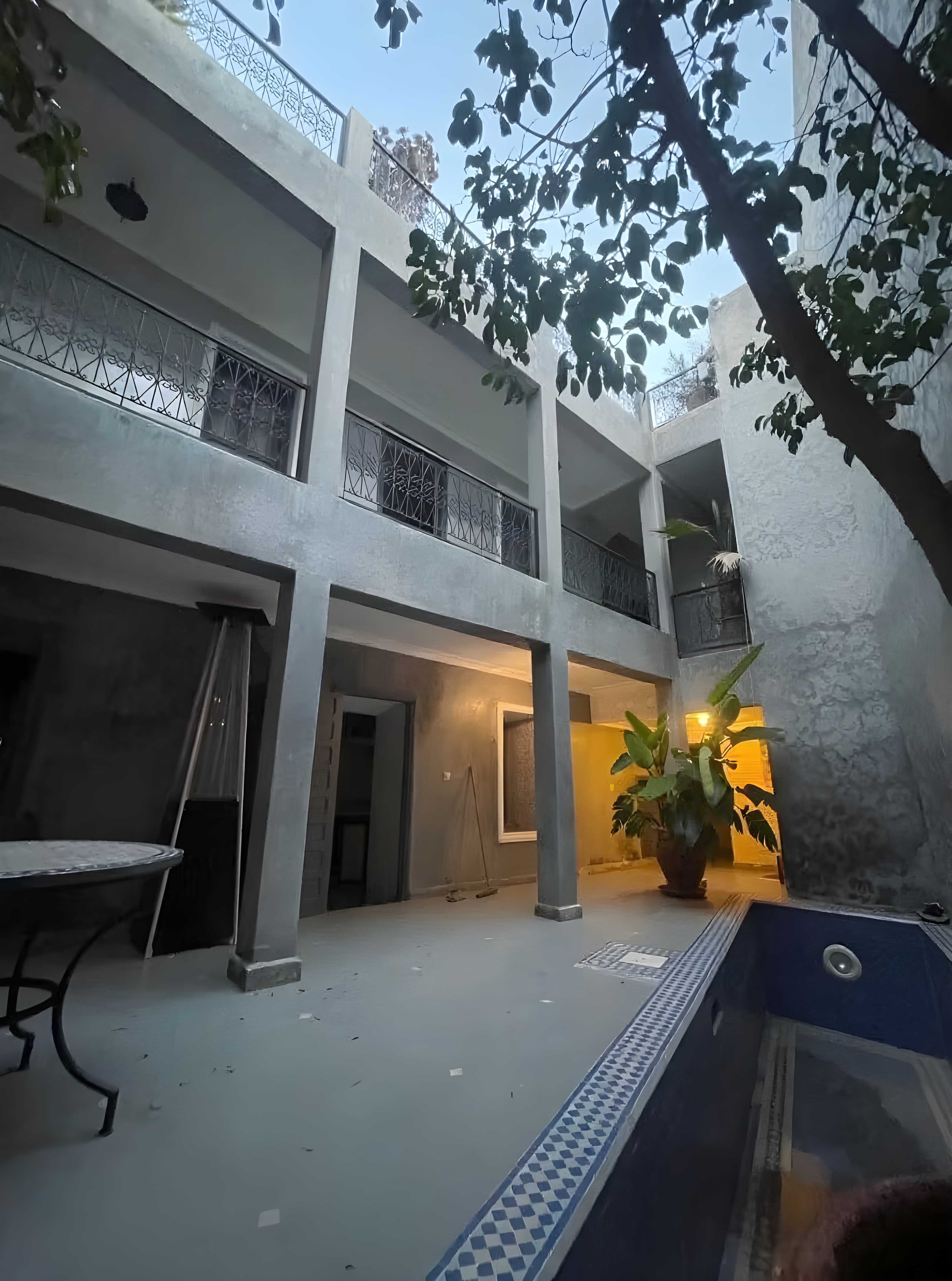 Open courtyard with balconies, pool, foliage, and seating in a Rmila riad.