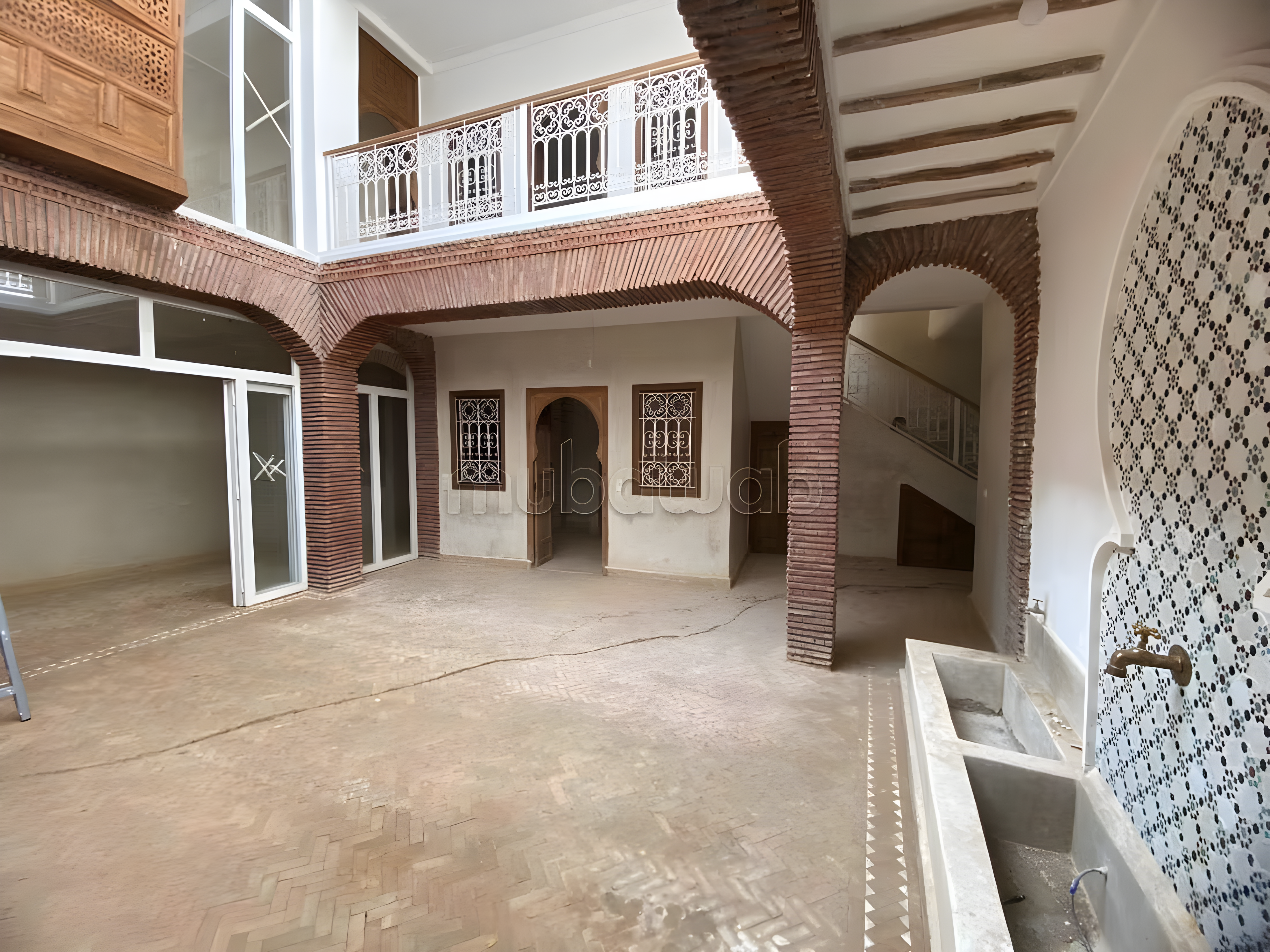 Courtyard of a guesthouse in Arset Ben Chebli, Marrakech with tiled walls and balconies.