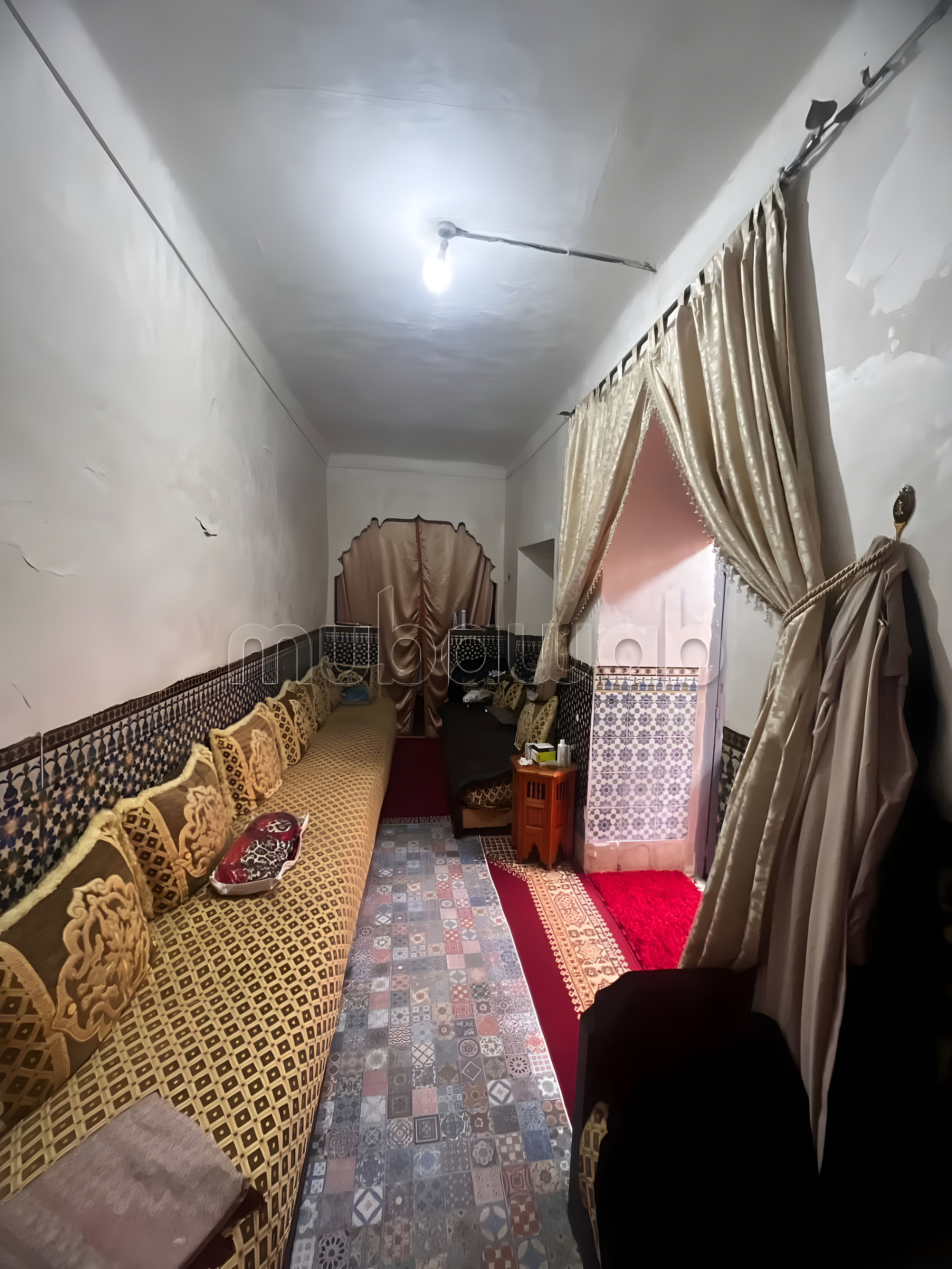 Narrow salon with Moroccan seating and patterned tiles in Ben Saleh.