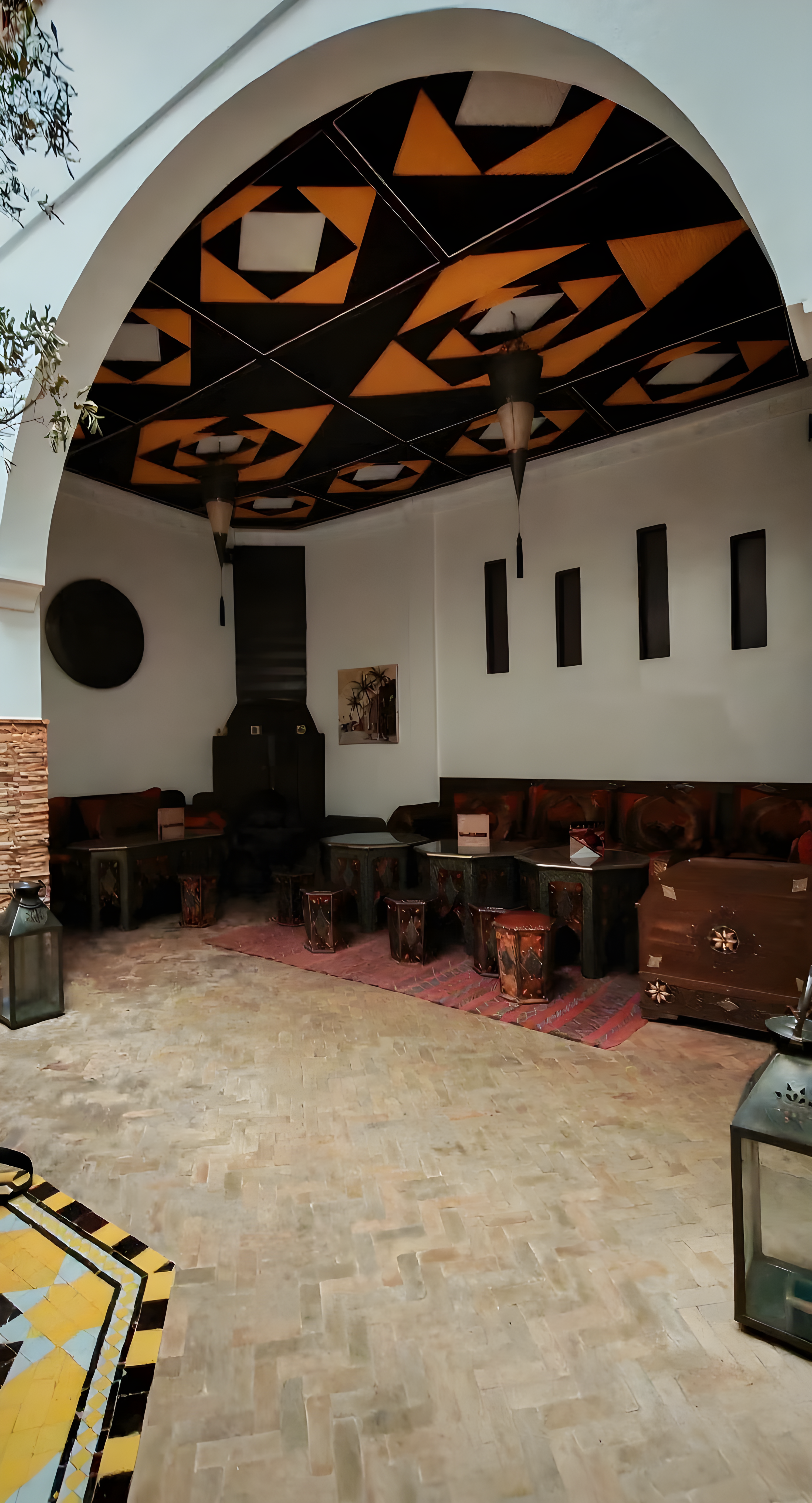 Moroccan-style guesthouse patio in Rmila with wooden furniture and geometric ceiling.