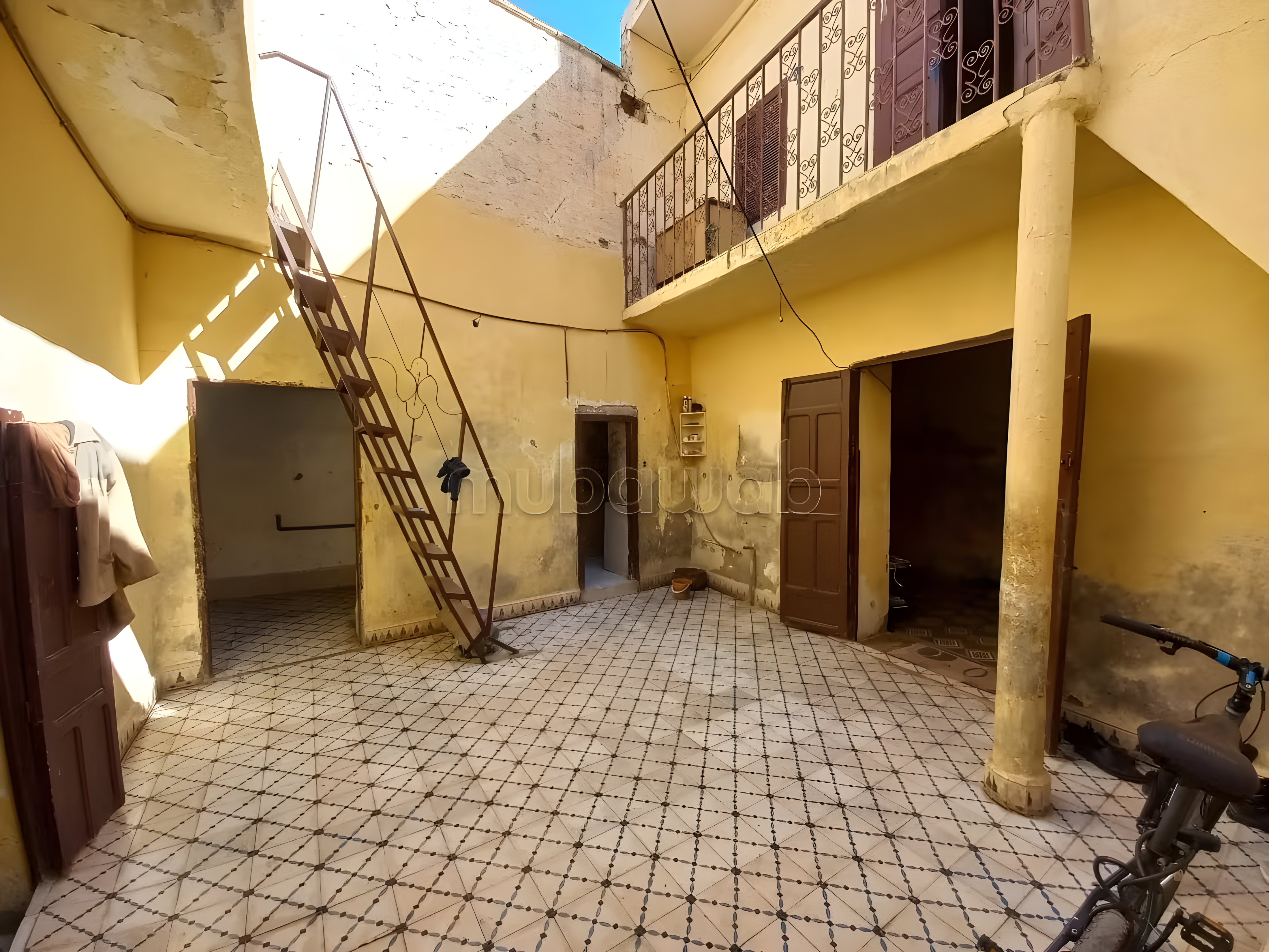 Courtyard in Ksibat Nhas guesthouse with tiled flooring and staircase.