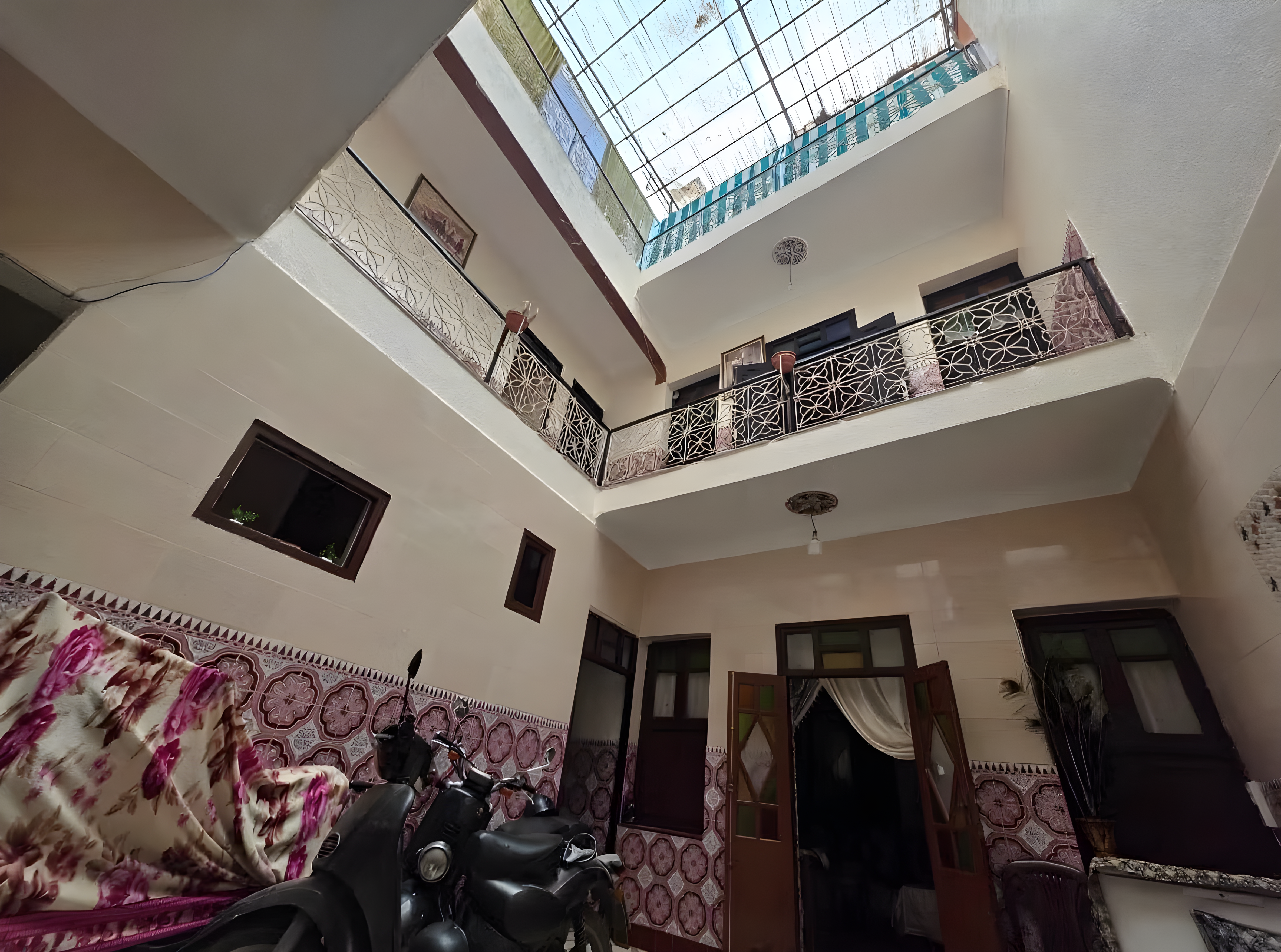 Innenhof mit Fliesen, Geländer, Dach und Motorrad in Moulay Lyazid.