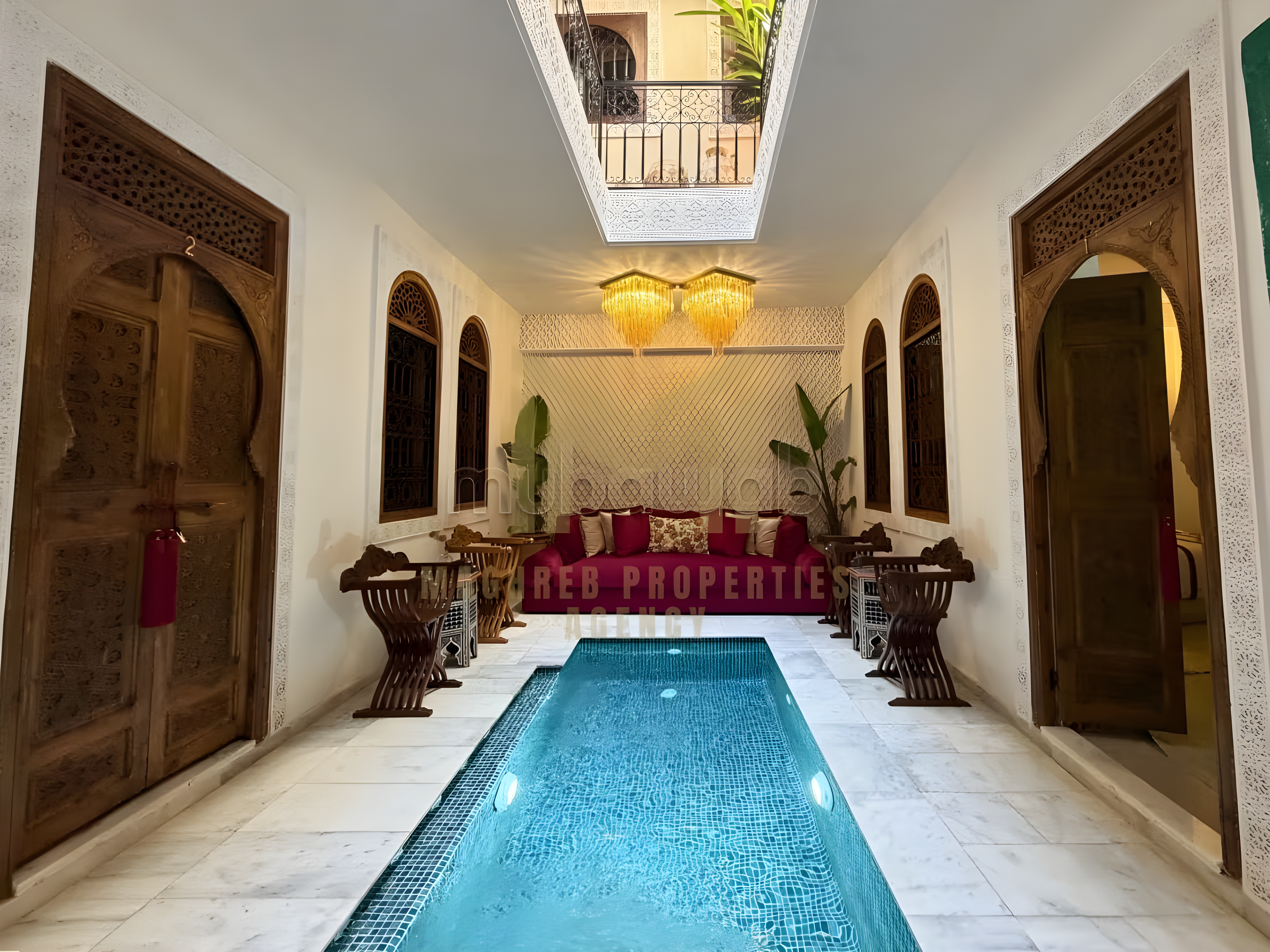 Courtyard with pool, wooden doors, and chandelier in Ksibat Nhas guesthouse.