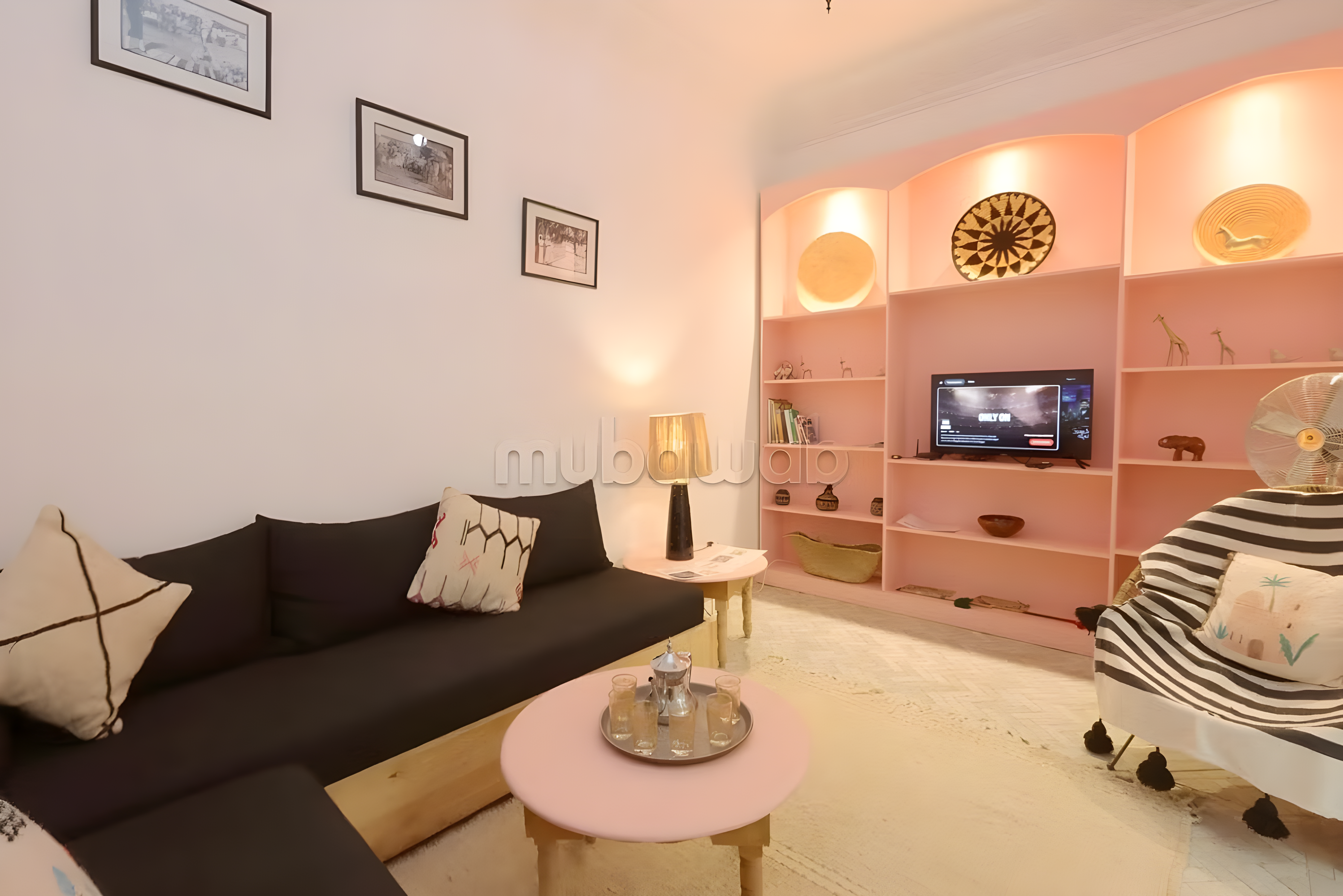 Salon mit schwarzem Sofa, rosa Regalen und rundem Couchtisch im Gästehaus Rahba Kedima.