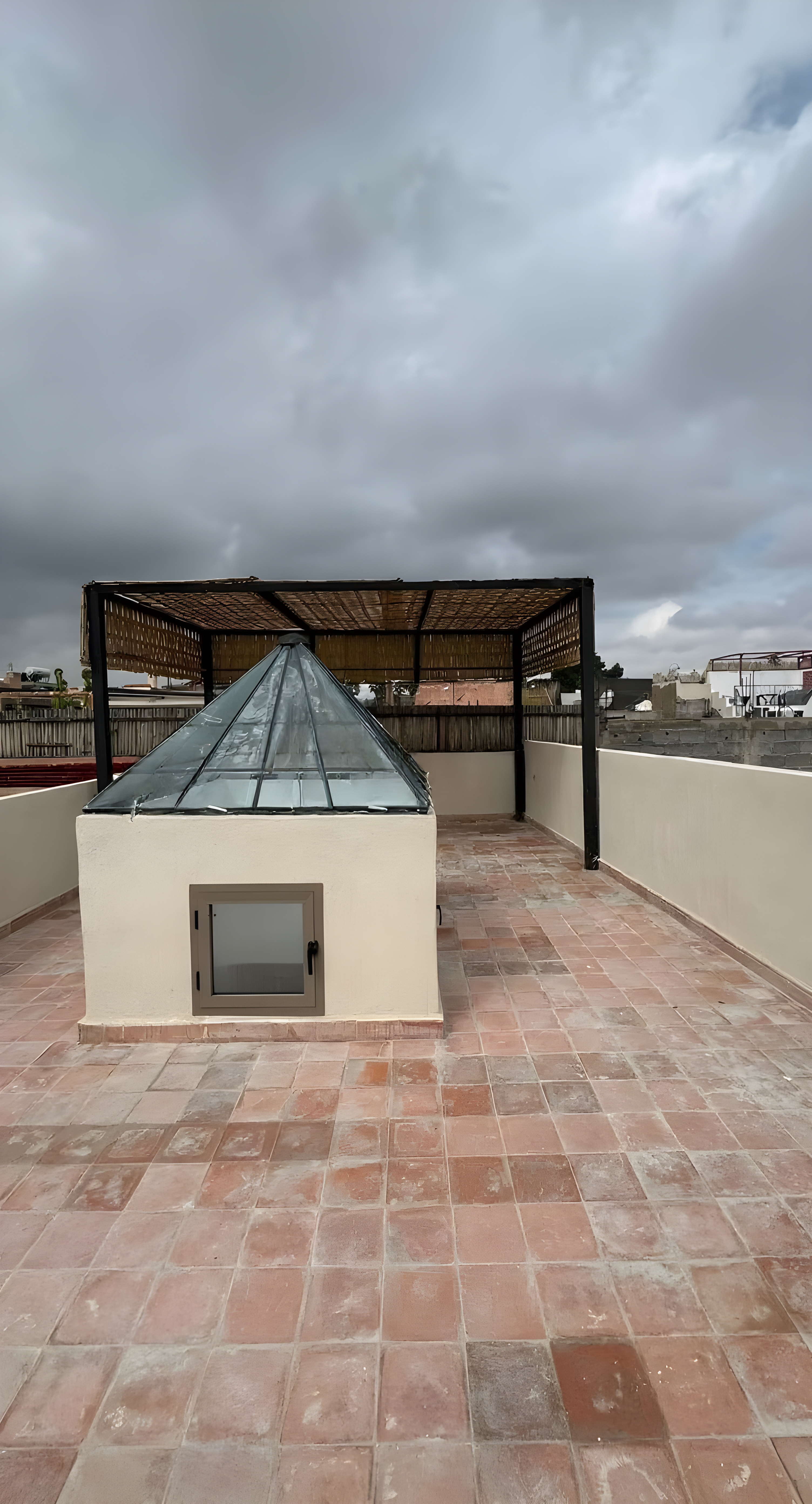 Rooftop with terracotta flooring, pergola, and glass skylight in Moulay Lyazid guesthouse.