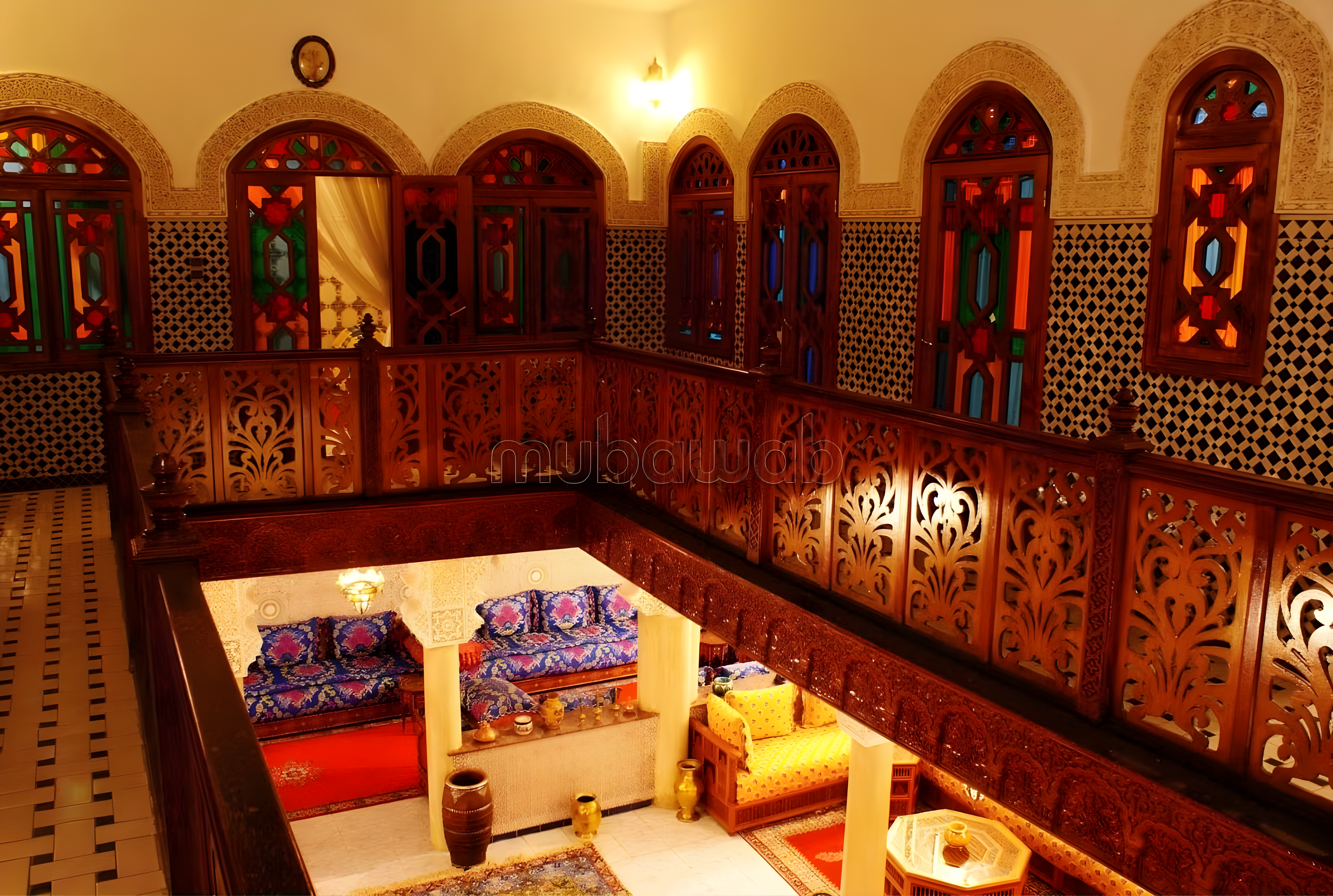 Moroccan courtyard with wooden latticework and colorful stained glass in Guéliz guesthouse.