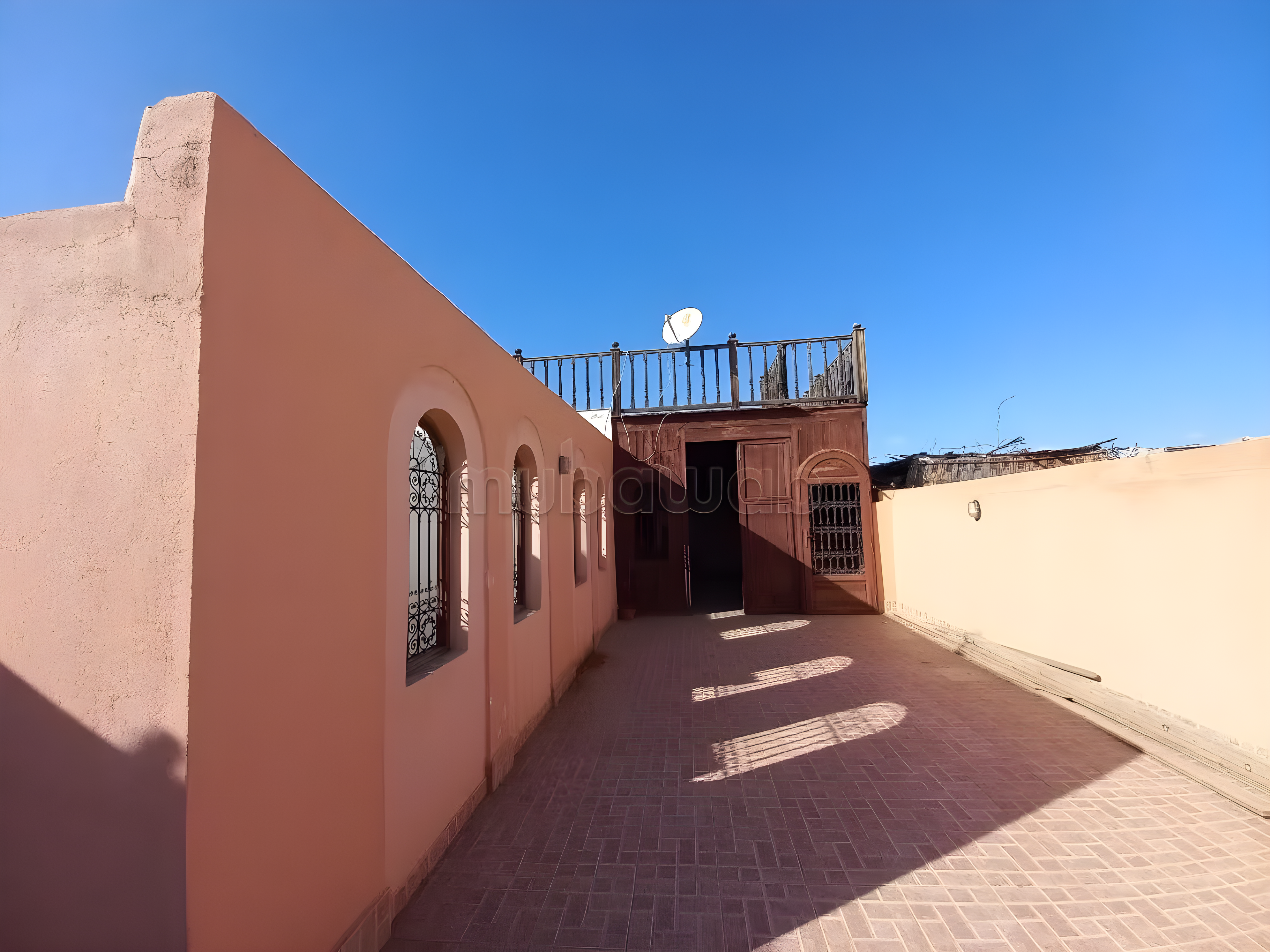 Rooftop of Sidi Mansour guesthouse with tiled floor and arched windows.
