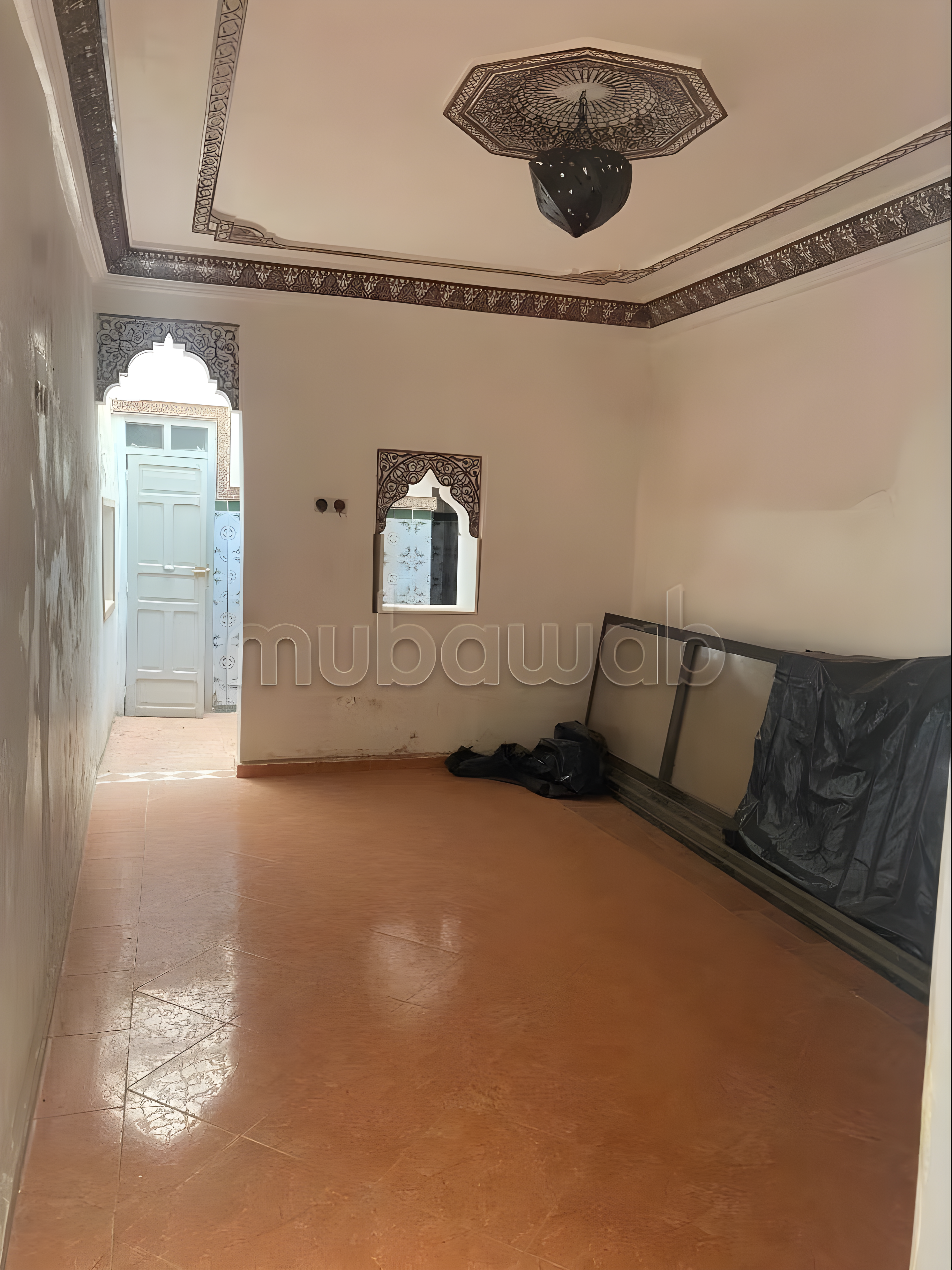 Empty Moroccan salon with tiles and arched doorway in Jnan Ben Chagra guesthouse.