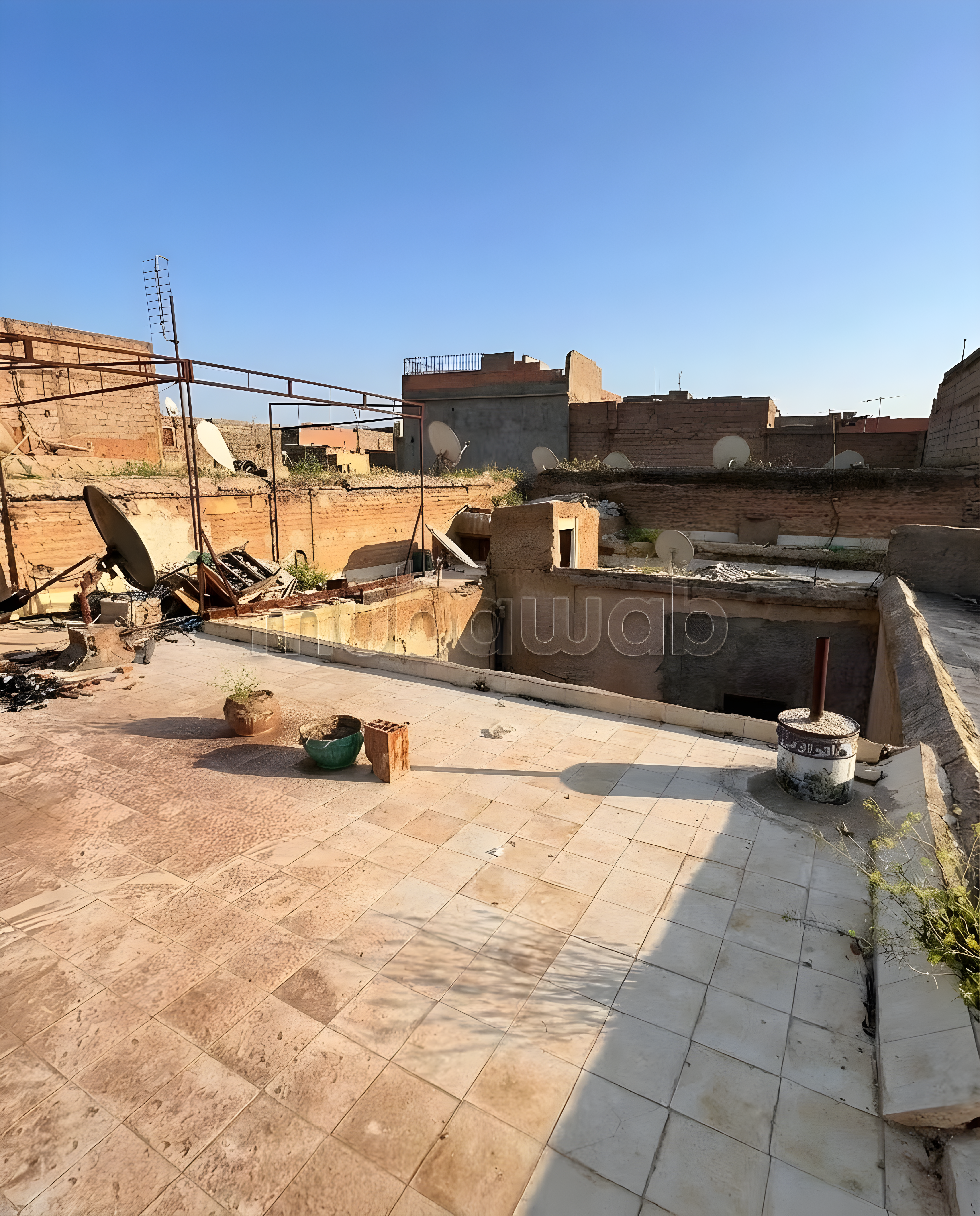 Rooftop of Jnan Ben Chagra guesthouse with tiles and satellite dishes.
